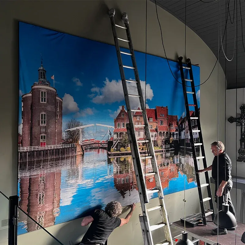 Monteur drukt de rand van het doek in het profiel van het frame