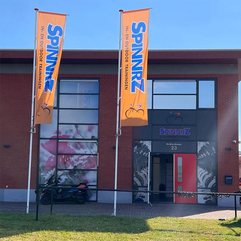 Twee oranje baniervlaggen aan de gevel van een sportschool