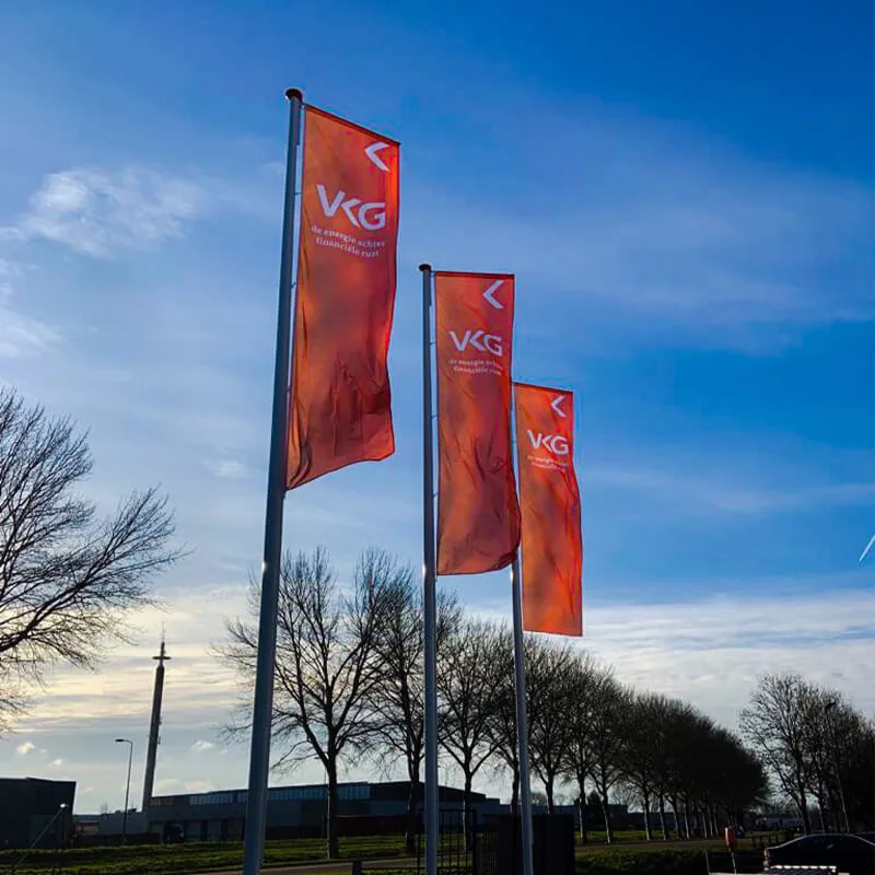 Drie rode baniervlaggen op masten langs de weg in de schemer
