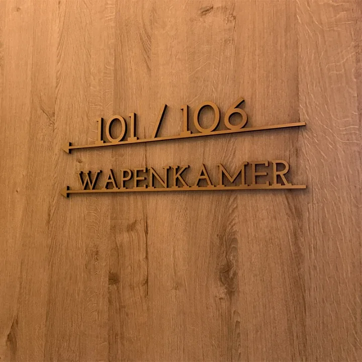 Uitgefreesde letters Wapenkamer met kamernummers op een houten wand