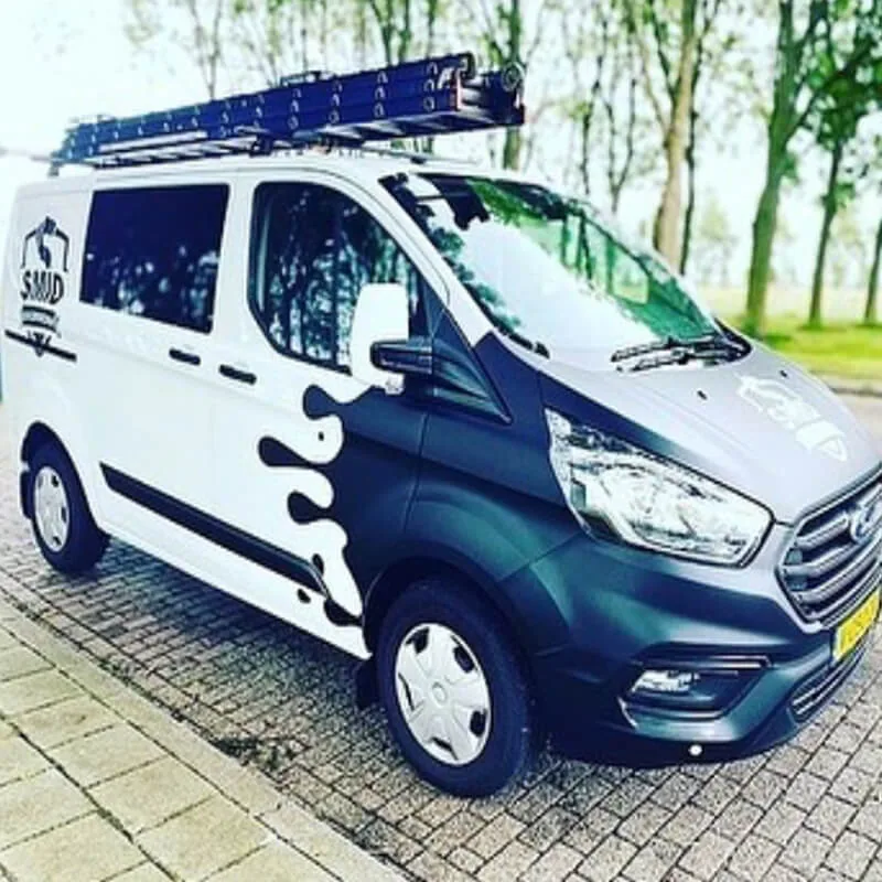 Witte werkbus met een donkerblauwe halve wrap met vloeiende vormen over de neus en het voorportier