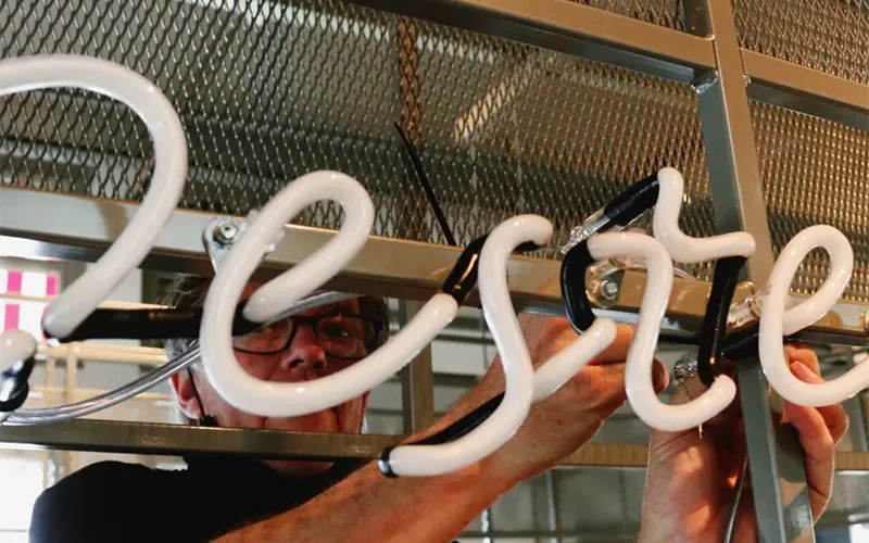 Vakman monteert witte neonletters in de werkplaats