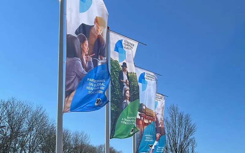 Rij bedrukte vlaggen aan masten tegen een blauwe lucht