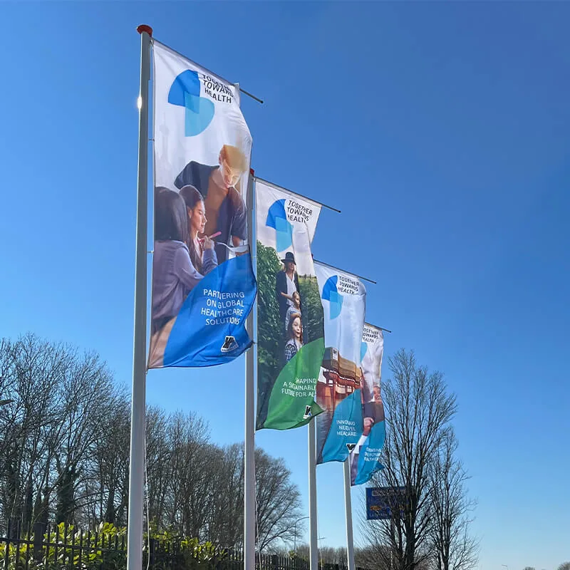 Rij bedrukte mastvlaggen langs de oprit van een bedrijfsterrein