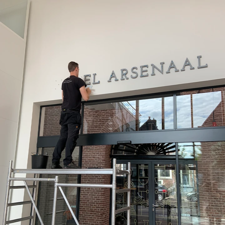 Monteur plaatst luxe messing letters van Hotel Arsenaal boven de entree