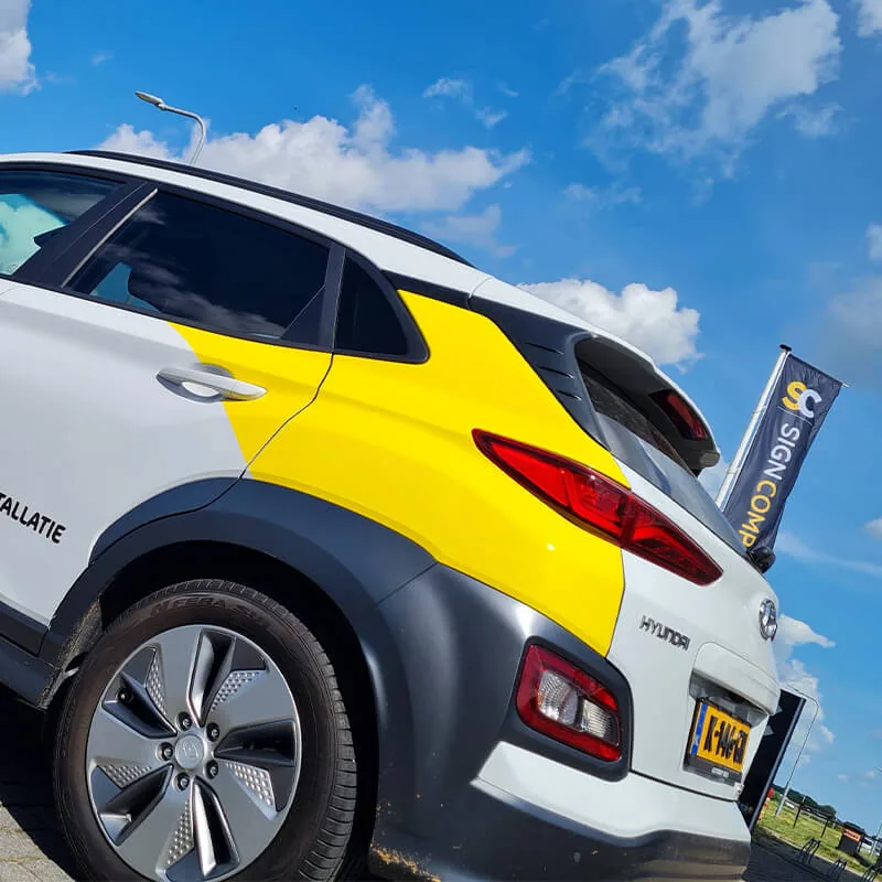 Witte Hyundai Kona met een geel kleurvlak over de achterklep en de zijkant