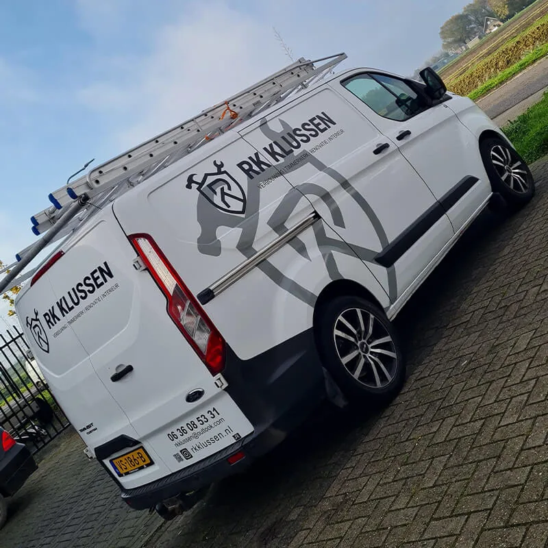 Witte werkbus met een groot grijs RK Klussen-logo op de zijkant en contactgegevens op de achterdeuren