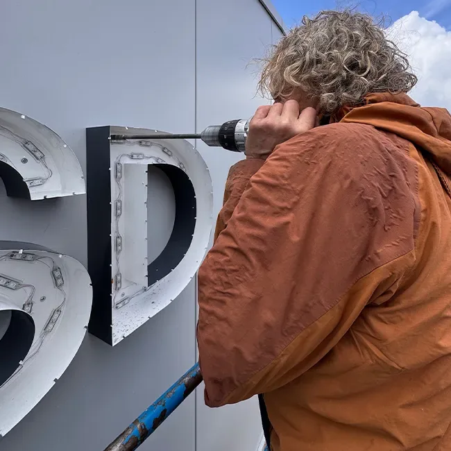 Monteur schroeft een doosletter D vast, de LED-modules zitten zichtbaar in de bak