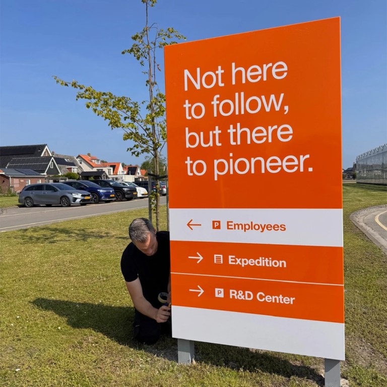 Monteur plaatst een oranje zuil op locatie in Andijk