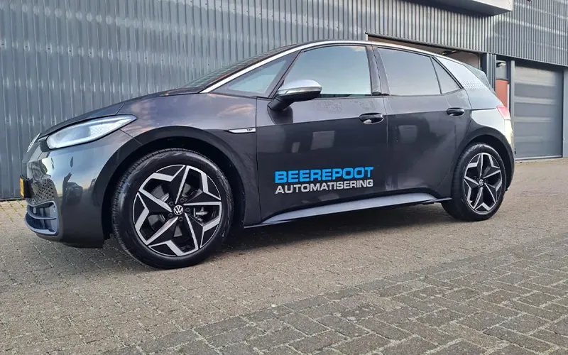 Donkergrijze personenauto met bedrijfsbelettering op de zijkant