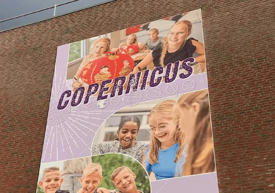 Spandoekframe met het schooldoek van Copernicus op een bakstenen gevel
