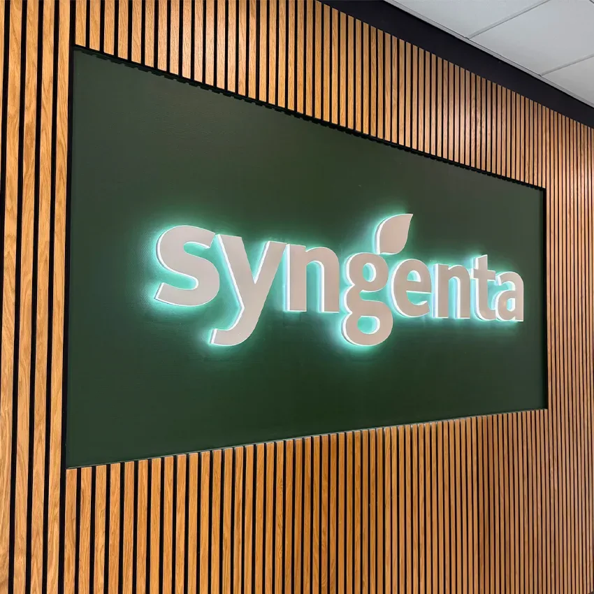 Syngenta-letters met halo-verlichting op een donkergroen paneel binnen