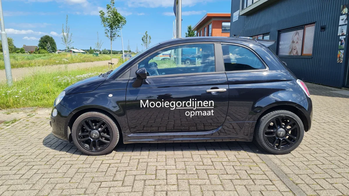 Zwarte Fiat 500 met witte belettering Mooiegordijnen op maat op het portier