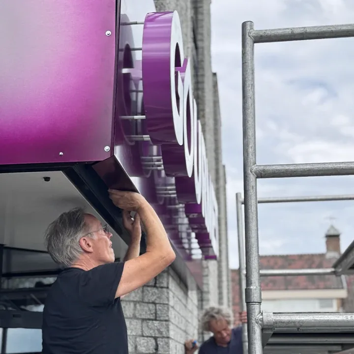 Monteur schroeft de paarse lichtbak van onderaf vast