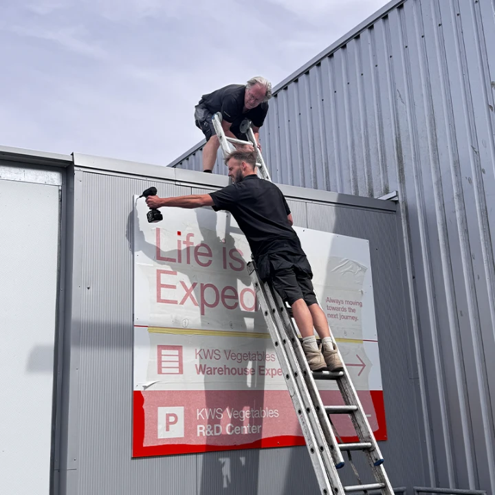 Monteur van Sign Company plaatst een reclamebord tijdens de montagefase