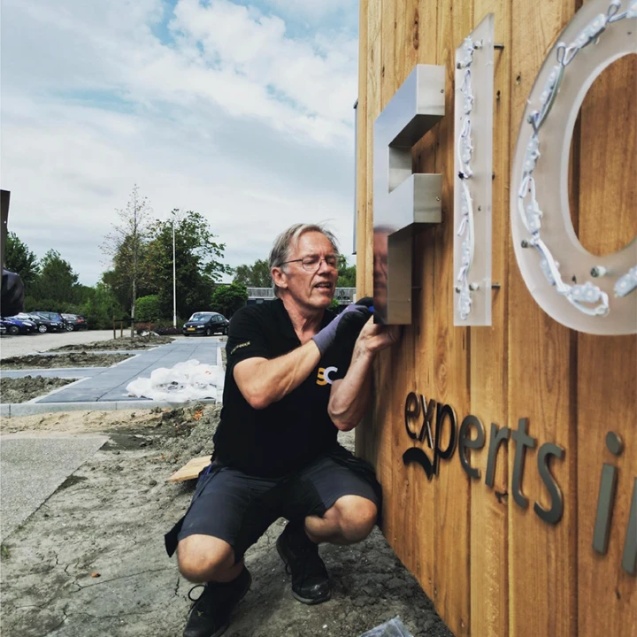 Vakman monteert doosletters op gevel