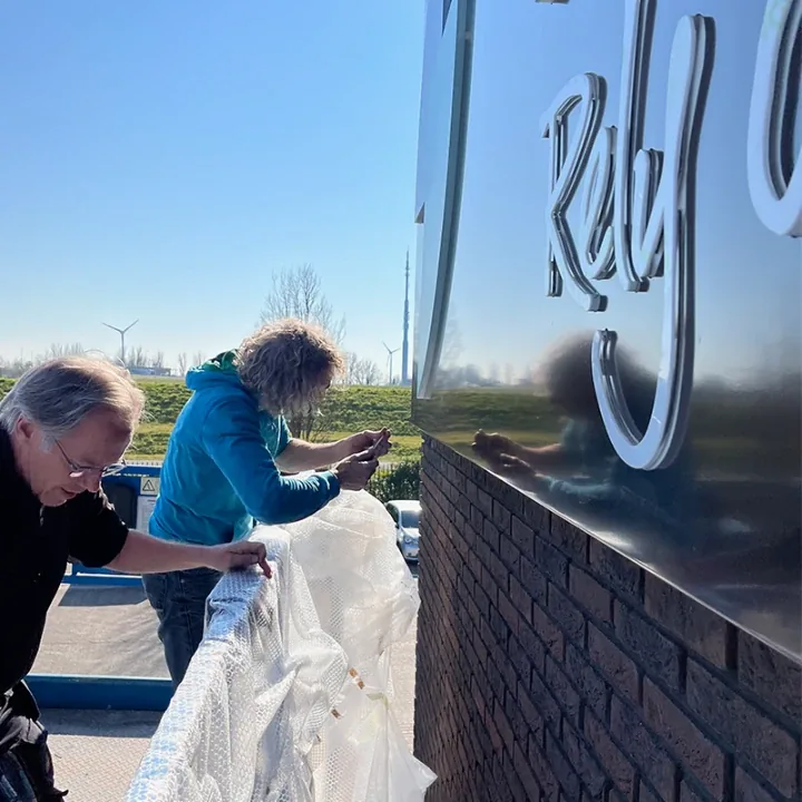 Twee monteurs pakken RVS-letters uit voor de gevel