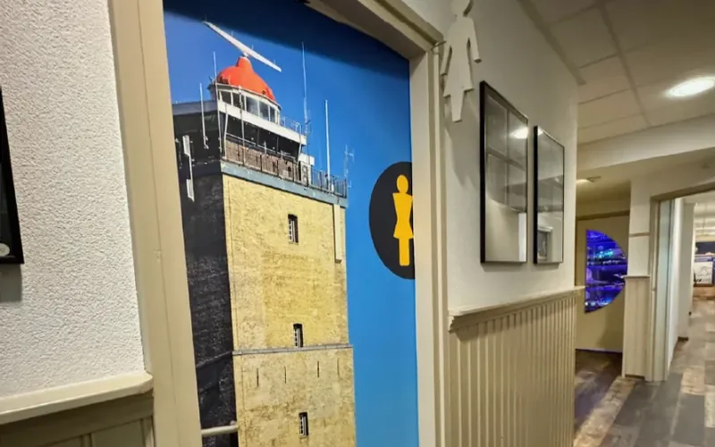 Gang met een fotoprint van een vuurtoren op de deur en een pictogram ernaast