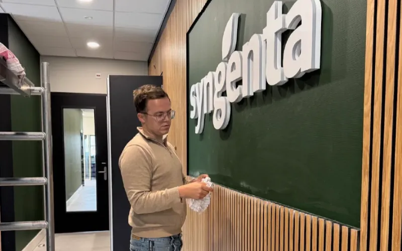 Witte 3D-letters van een bedrijfsnaam op een groene wand in een kantoorhal