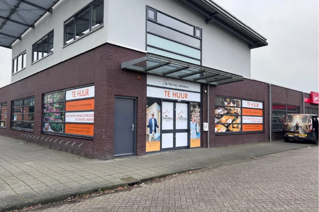 Bedrijfspand met te-huur-borden en raamreclame van Vesting Makelaars