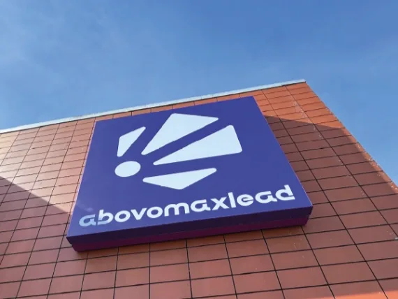 Blauwe lichtbak met het abovomaxlead-logo op de hoek van een bakstenen pand
