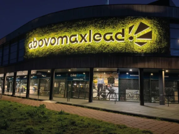 Verlichte letters abovomaxlead op een groene plantenwand, brandend in de avond