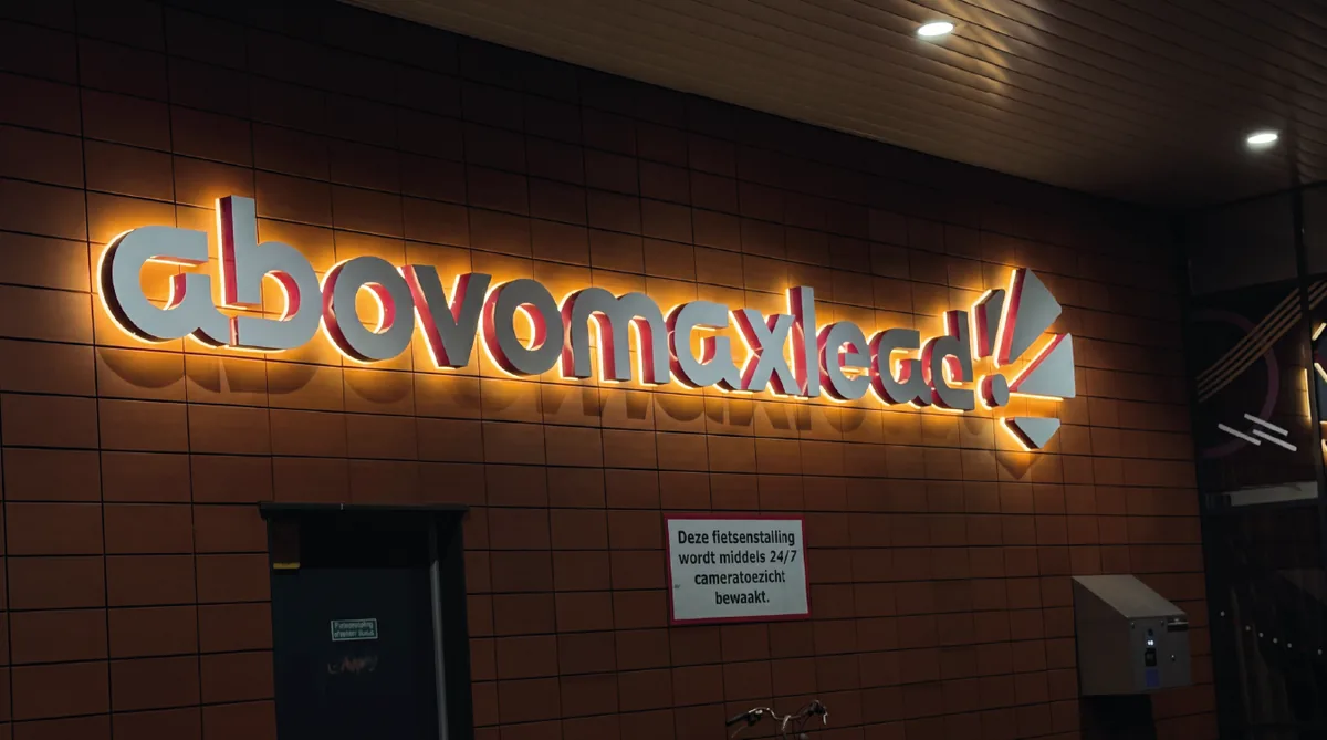 Indirect verlichte letters abovomaxlead met warme gloed tegen een bakstenen wand