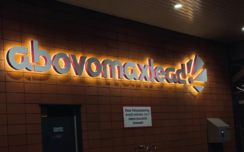 Gevelletters met een warme lichtrand op de tegelwand erachter, de letterfronten lichten zelf niet op