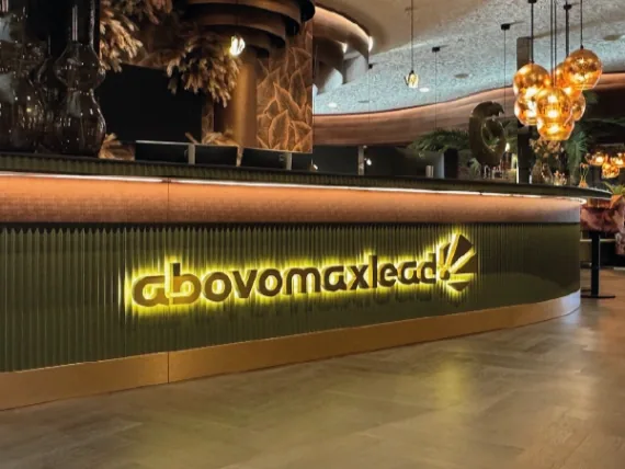 Gouden RVS-letters abovomaxlead met indirecte verlichting achter een bar
