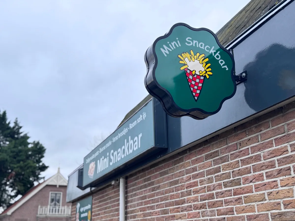 Groen uithangbord met ijshoorntje en de naam Mini Snackbar op de hoek van de gevel