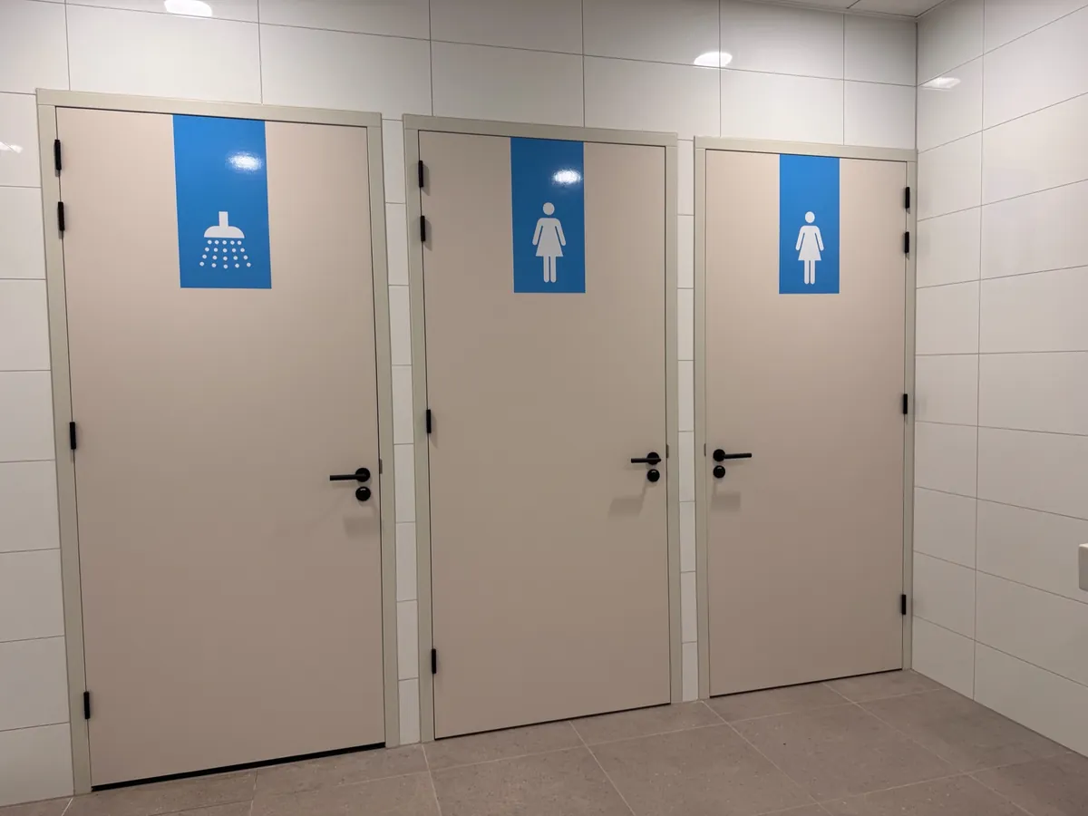 Drie deuren met blauwe pictogrammen voor douche en toiletten
