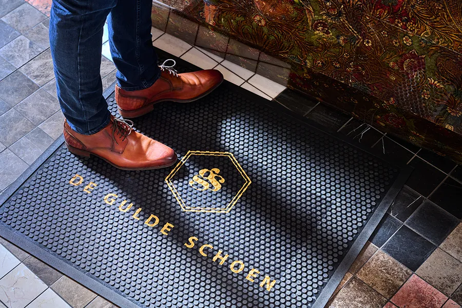 Rubber mat met logo in goud, binnen bij de deur
