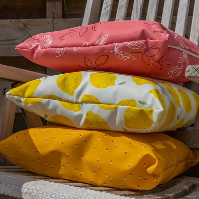 Bedrukte sierkussens buiten, drie verschillende prints op een houten tuinbank