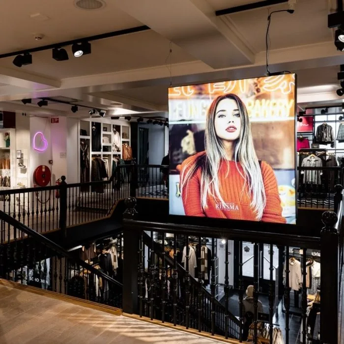 Verlicht LED-frame met bedrukte print, hangend boven een winkelvloer
