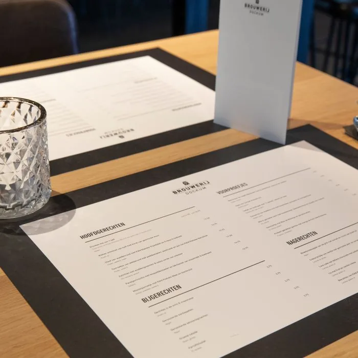 Bedrukte placemats op een restauranttafel, met menukaart en glaswerk