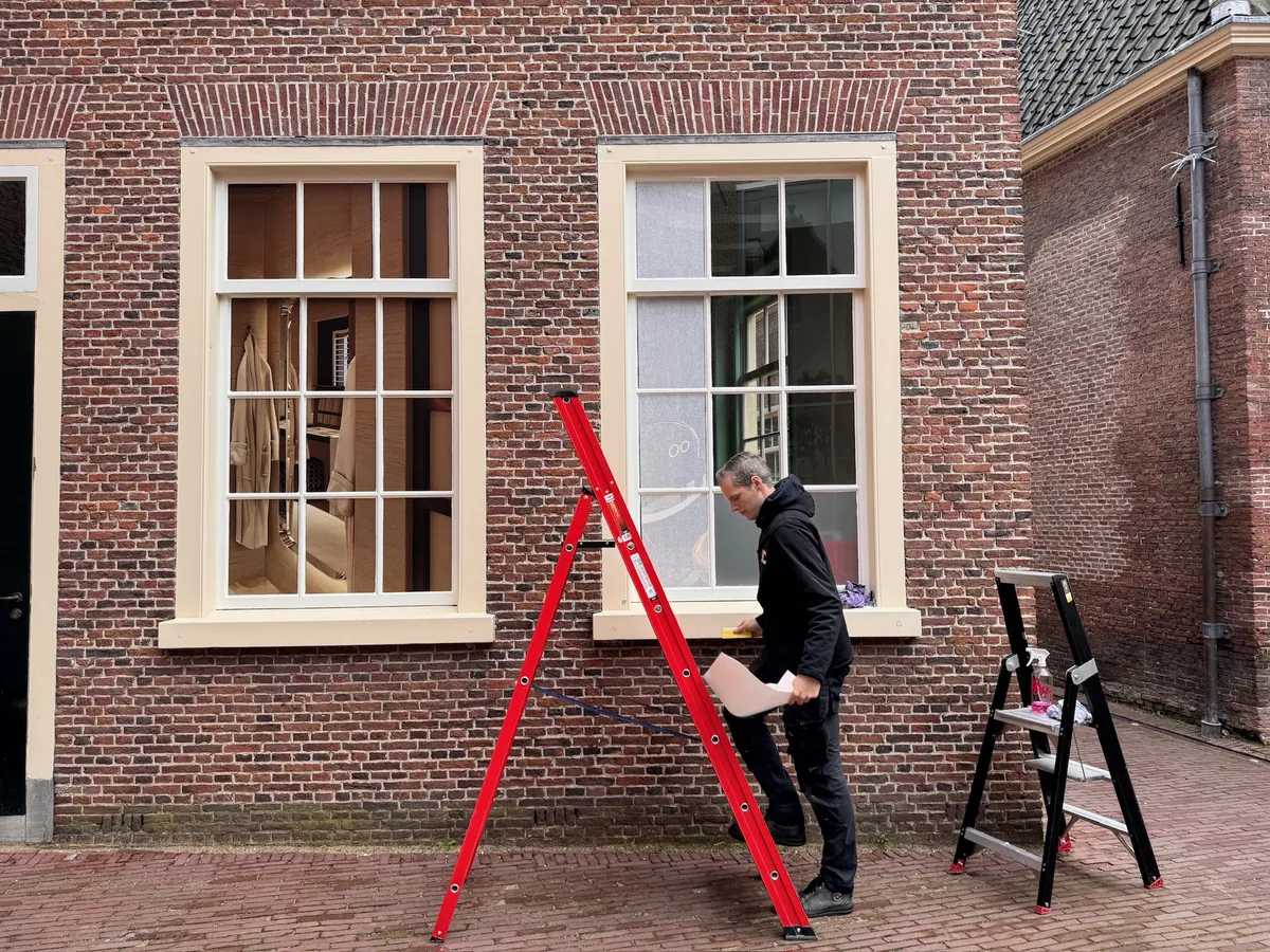 Monteur brengt een raambeeld van een hotelkamer aan op een raam