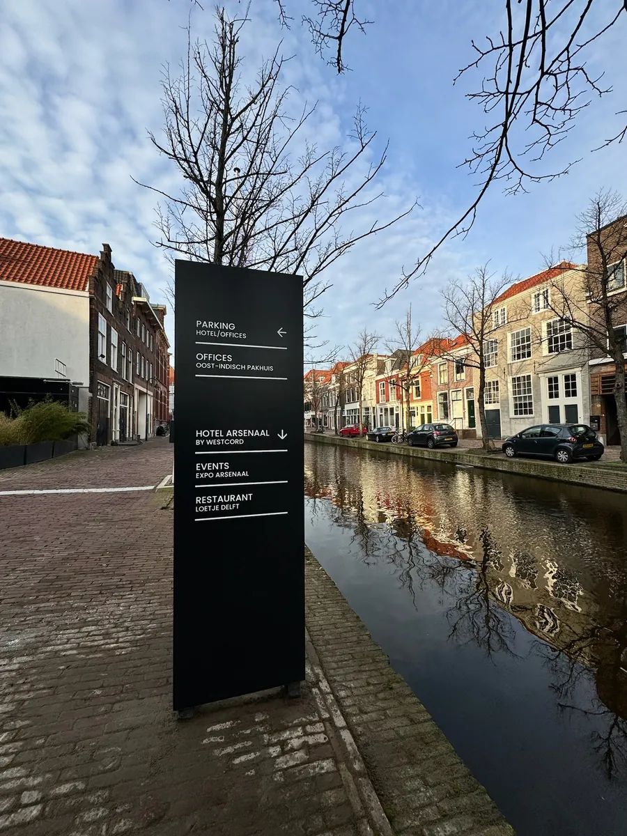 Bewegwijzeringszuil aan de gracht met pijlen naar parkeren en het hotel