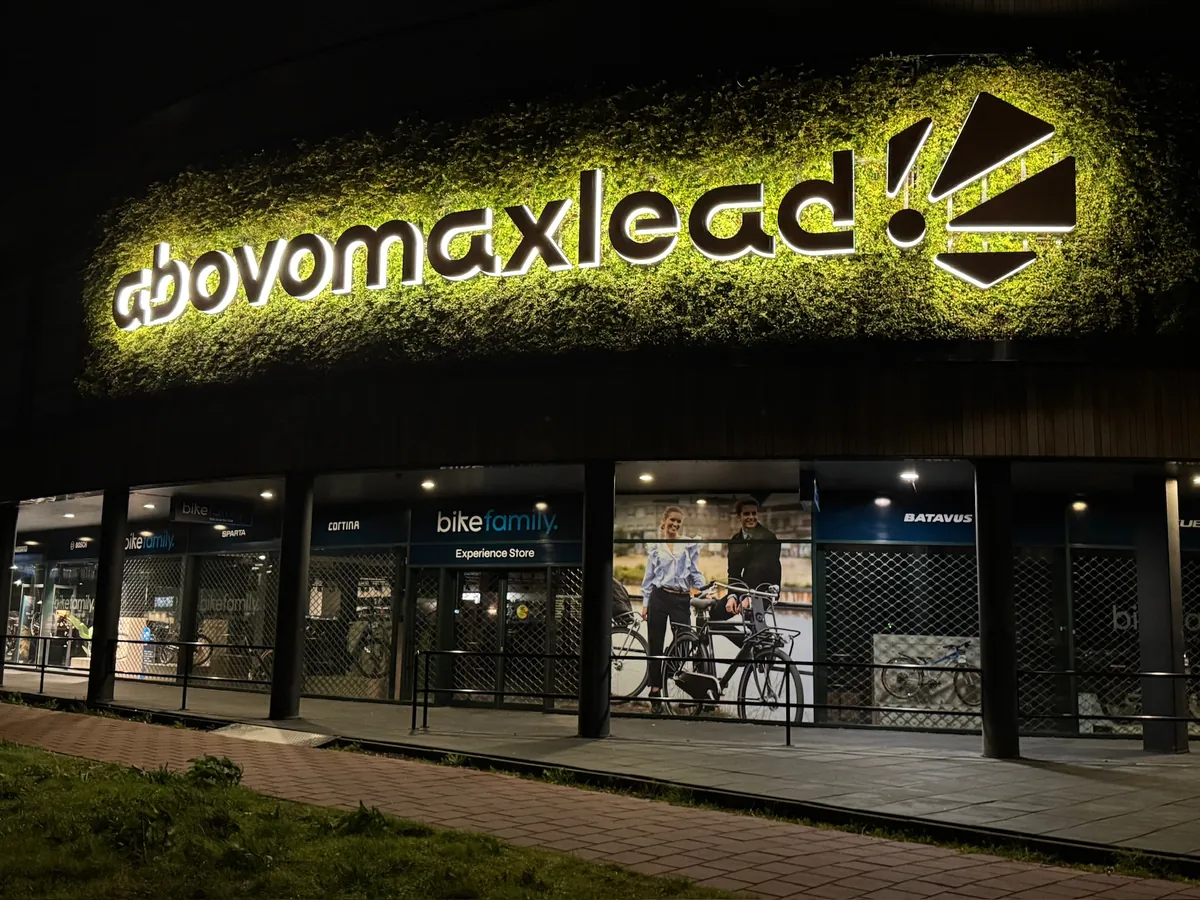 Verlichte letters abovomaxlead met beeldmerk boven een winkelpui in Hoorn bij avond