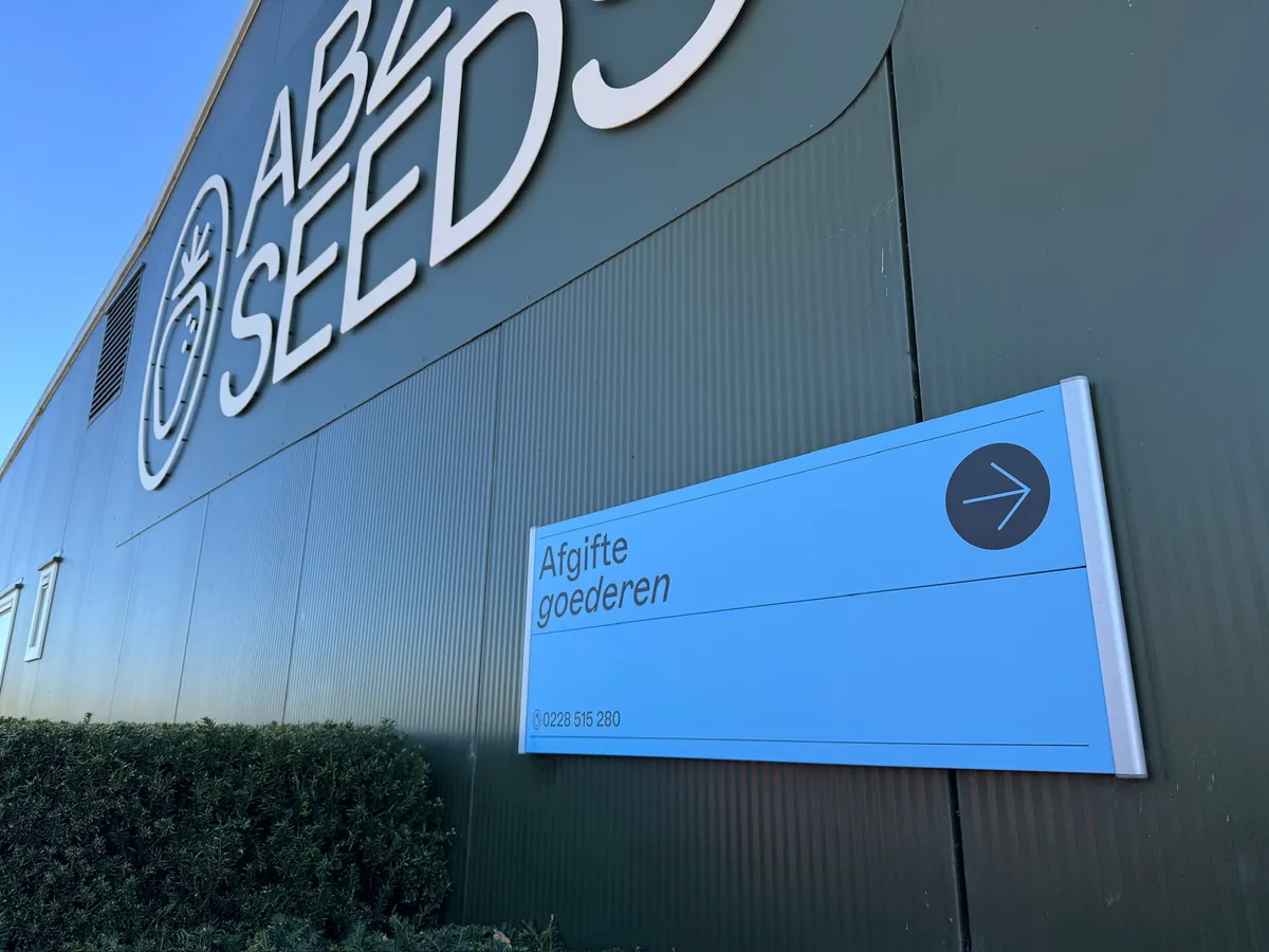 Witte letters ABZ SEEDS op de groene gevel met een blauw bord Afgifte goederen