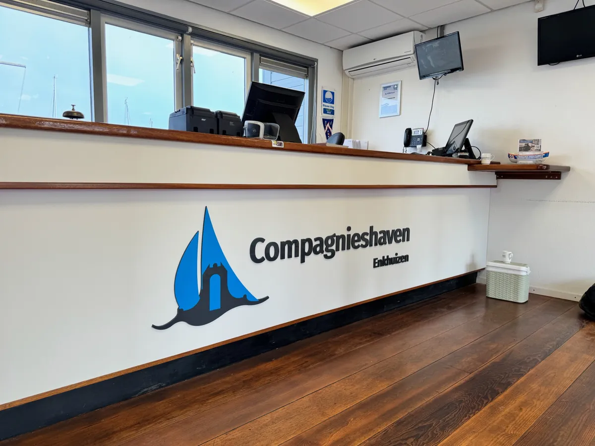 Logo Compagnieshaven Enkhuizen op de witte receptiebalie