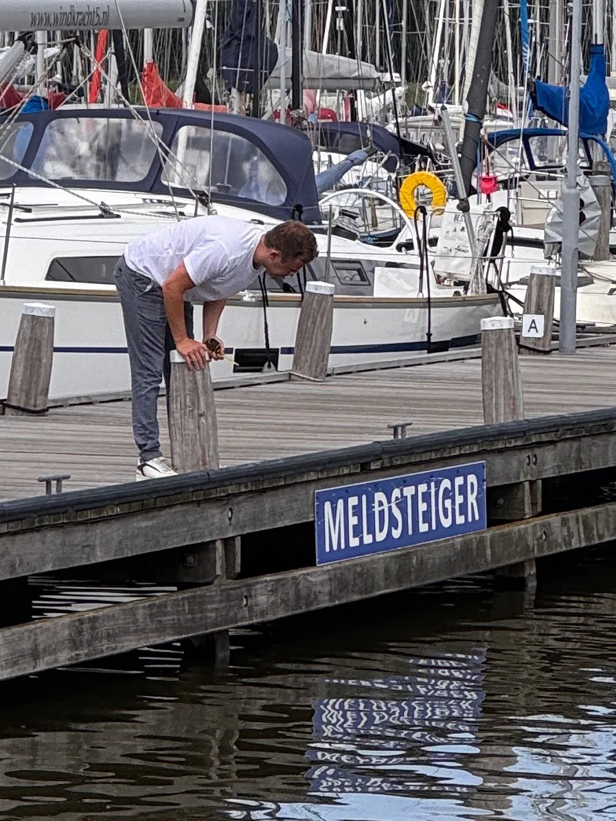 Monteur plaatst een bord Meldsteiger aan de steiger in de haven
