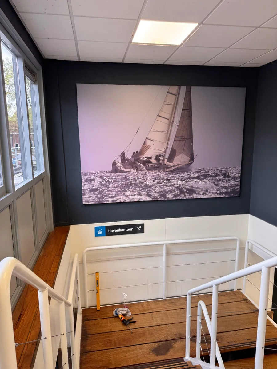 Grote zwart-witprint van een zeilboot boven het trapgat, met een bordje Havenkantoor