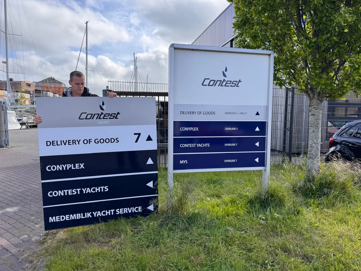 Monteur bij twee informatieborden van Contest met pijlen naar de gebouwen