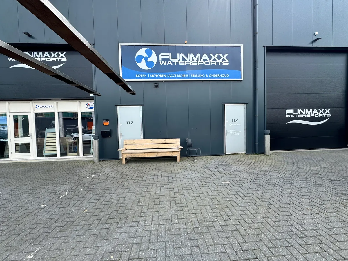 Bedrijfspand met het blauwe Funmaxx-bord boven de entree en het logo op de roldeur