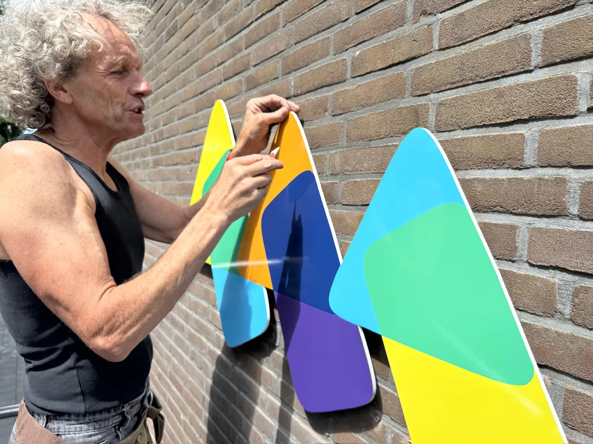 Monteur plaatst de kleurige delen van het logo op de bakstenen muur