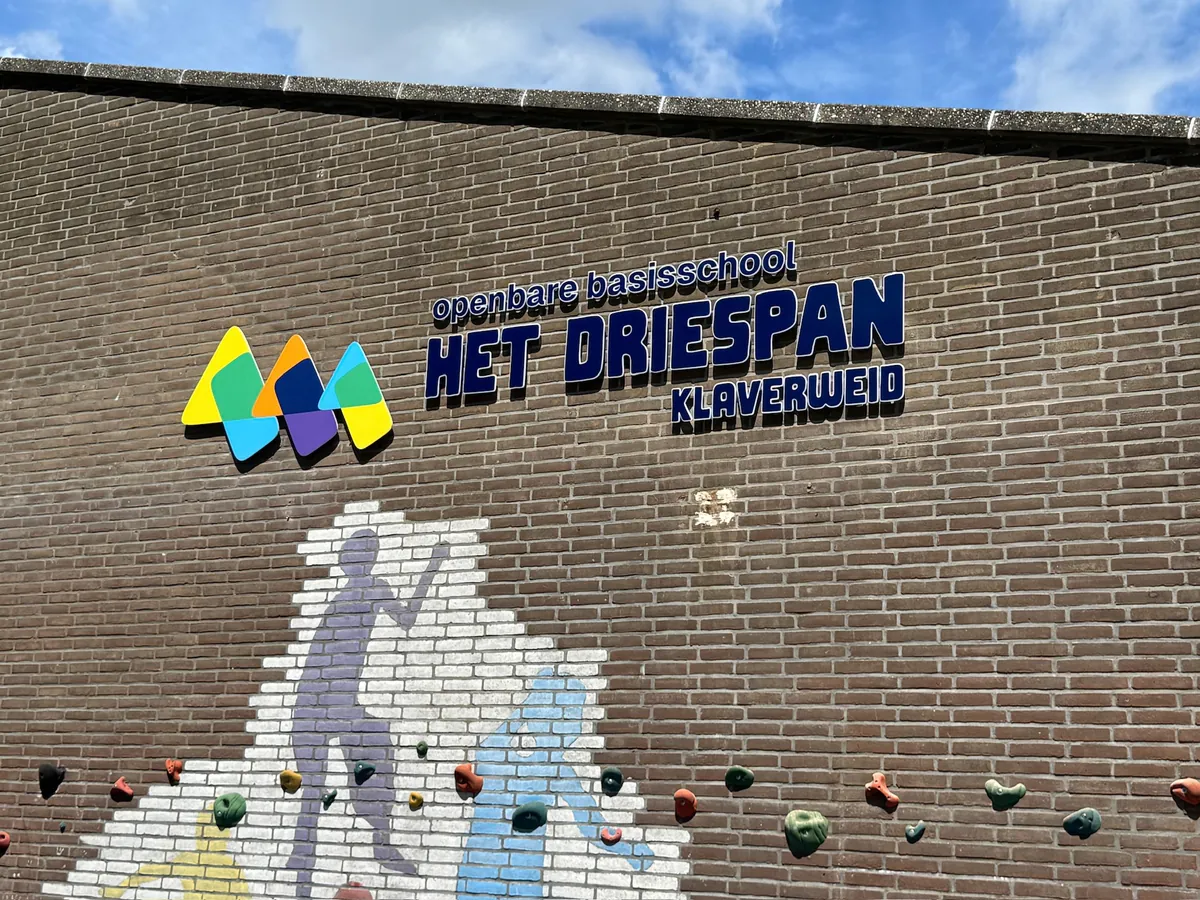 Logo en naam Het Driespan boven de muur met figuren en klimgrepen
