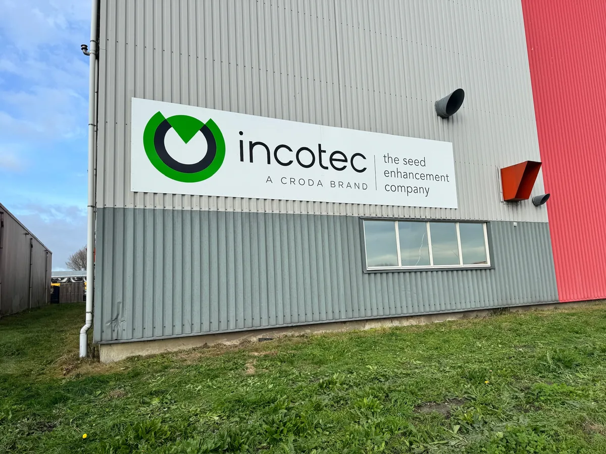 Wit bord met het incotec-logo op de gevel van de bedrijfshal, met gras ervoor