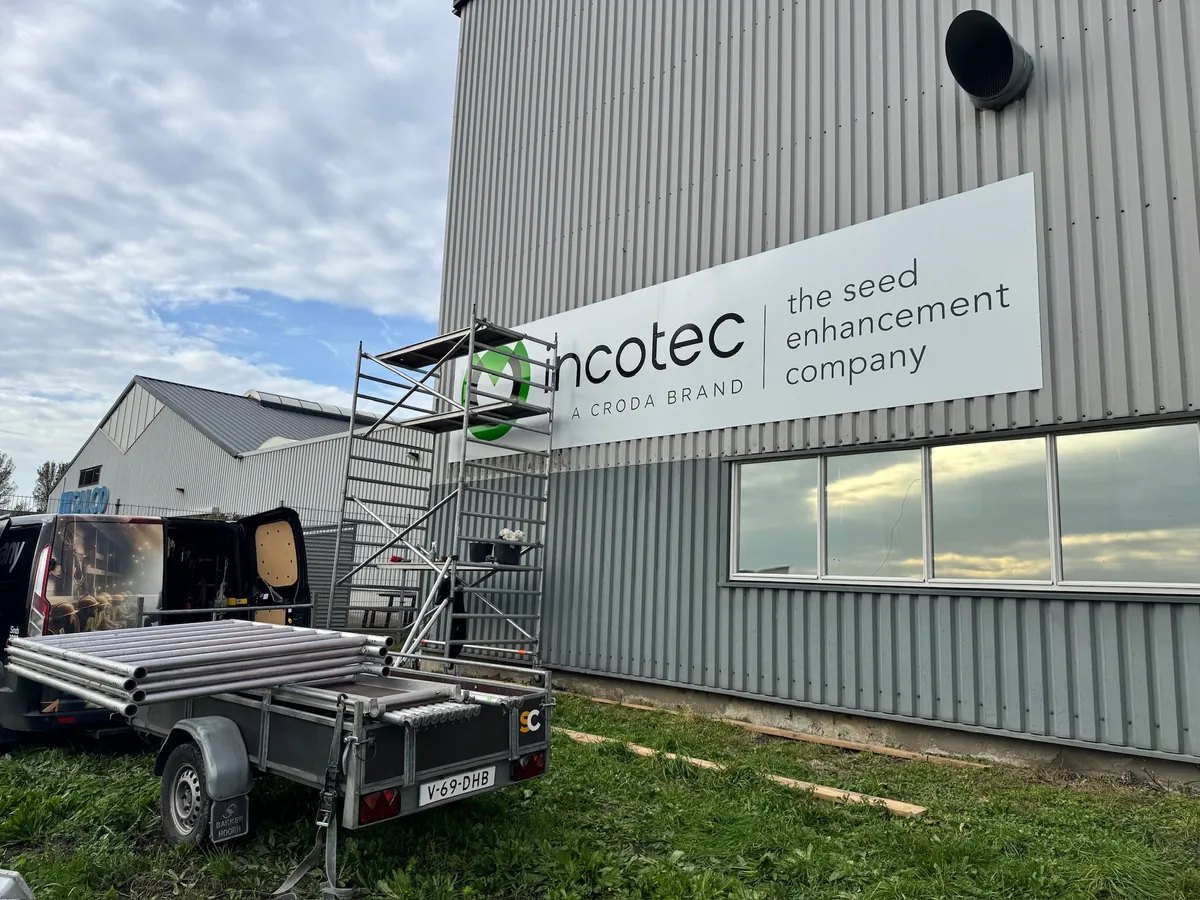 Groot incotec-bord op de hal met een steiger en aanhanger ervoor