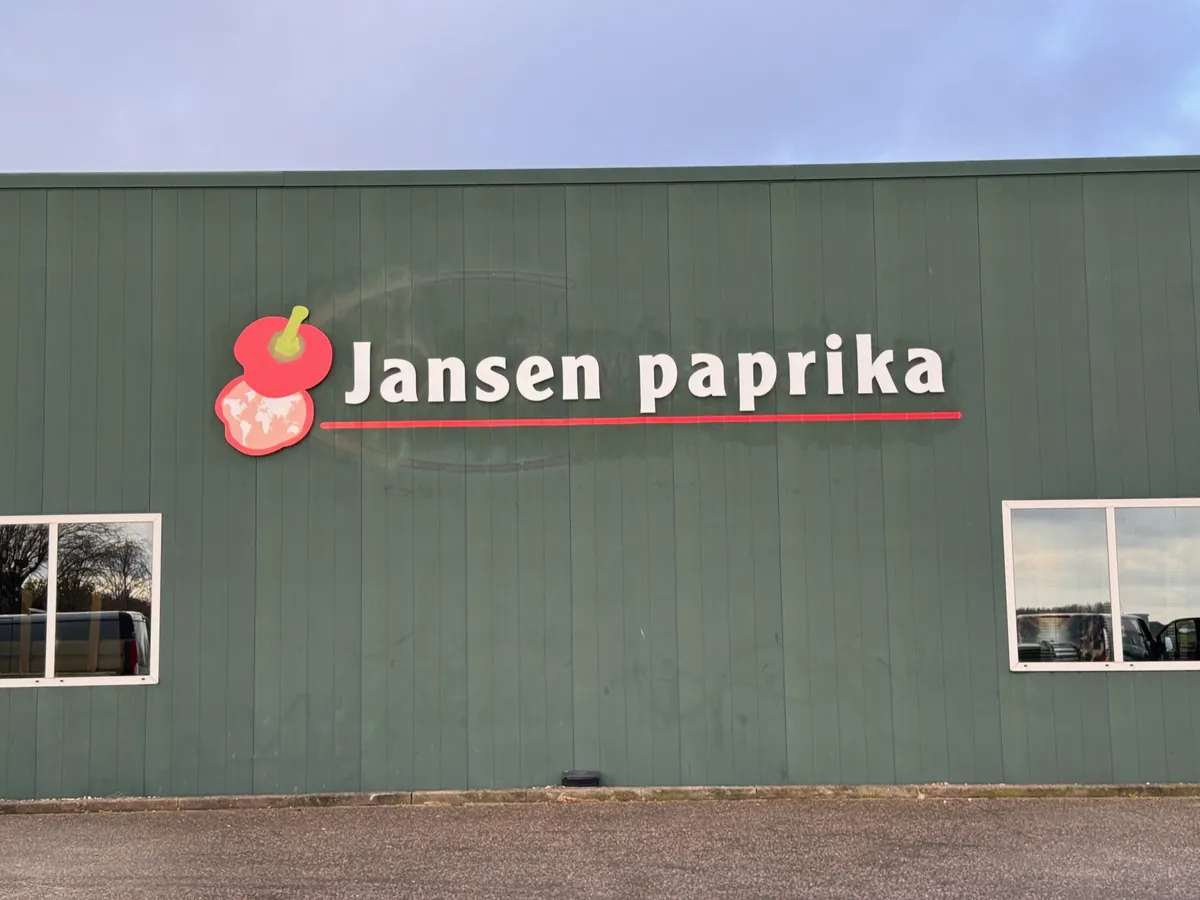 Groene loods met het logo en de naam Jansen paprika boven twee ramen