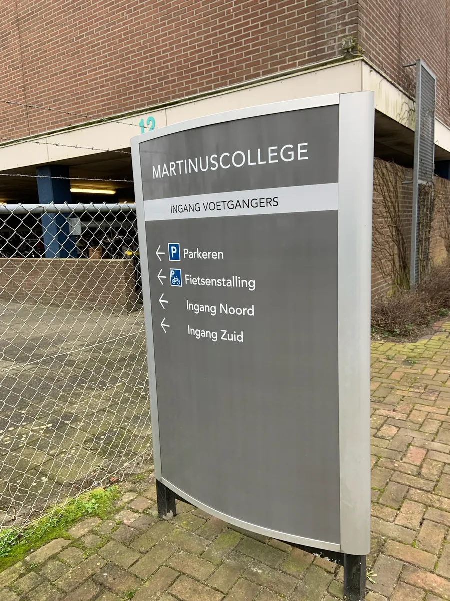 Grijze zuil Martinuscollege ingang voetgangers met pijlen